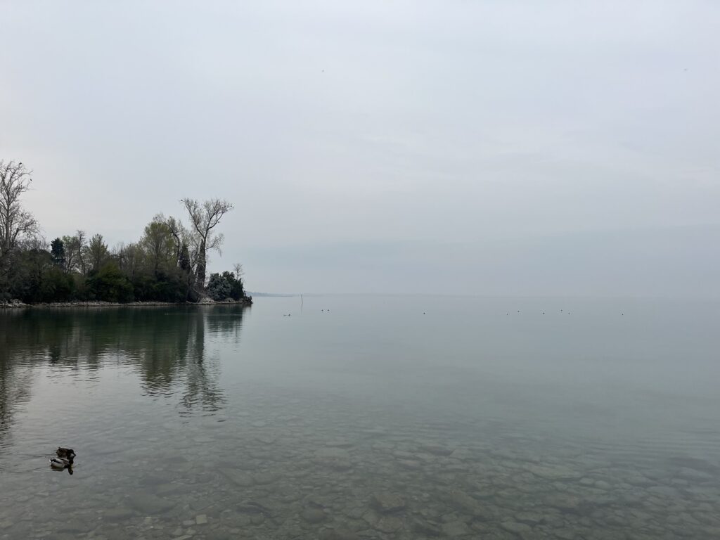 曇りの日のガルダ湖の写真。湖面から空にかけてグレーを基調としたグラデーションが広がる。